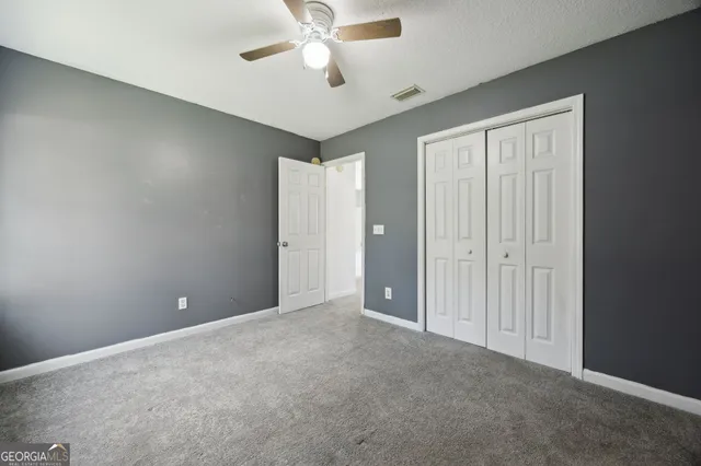 an empty room with windows and fan