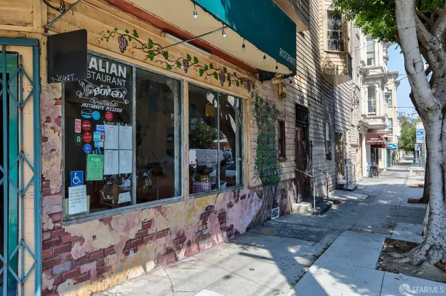 a view of city with the shops and cars parked in front of retail shops