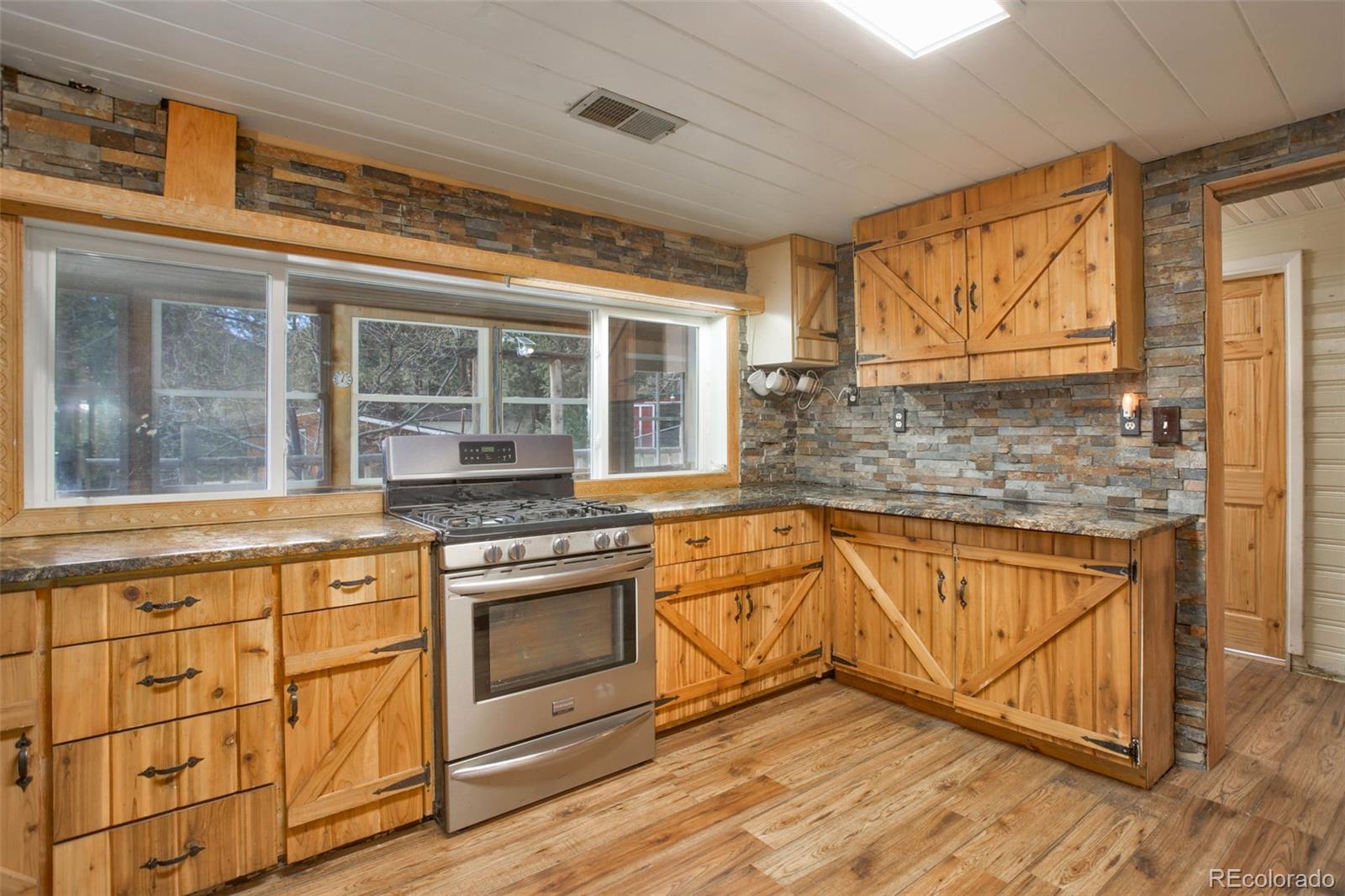 9399 Granzella Road Morrison, CO 80465 - Photo 13 of 41 a kitchen with stainless steel appliances granite countertop a stove and cabinets