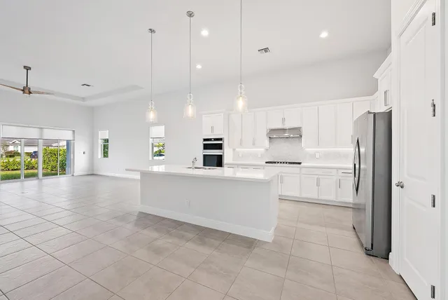 a large white kitchen with cabinets and a refrigerator