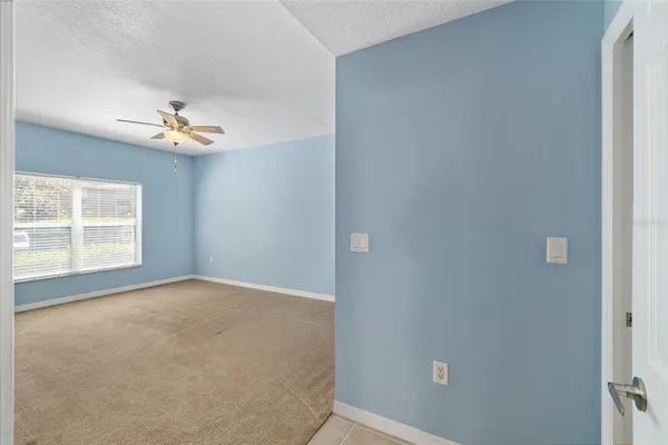 an empty room with chandelier fan and windows