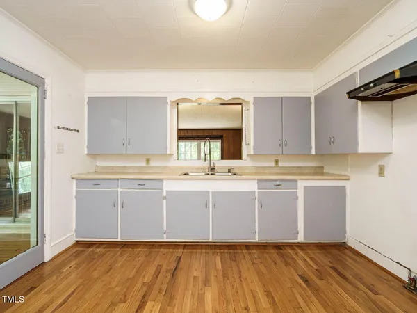 a kitchen with granite countertop a sink cabinets and wooden floor