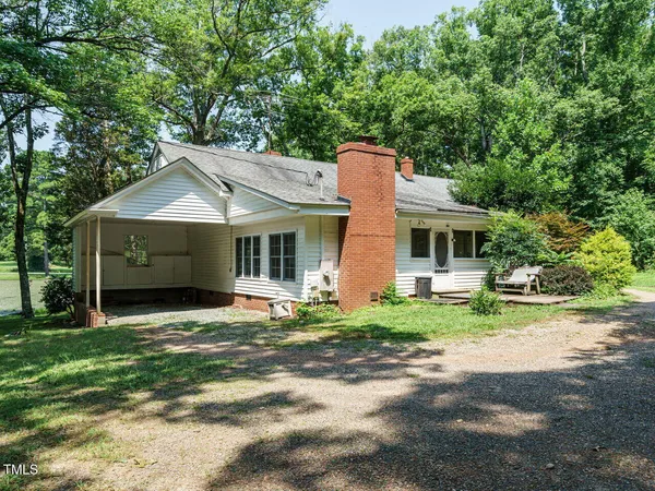 a front view of a house with a garden and trees