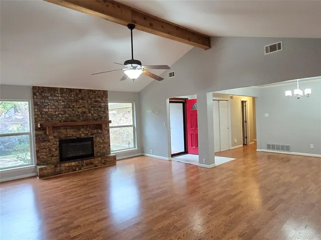 a view of an empty room with wooden floor fireplace and a window