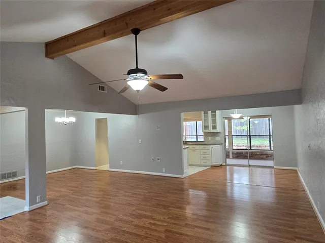 a view of an empty room with window and wooden floor