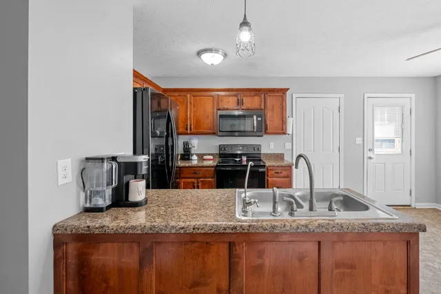 a kitchen with granite countertop a sink a counter top space cabinets and stainless steel appliances