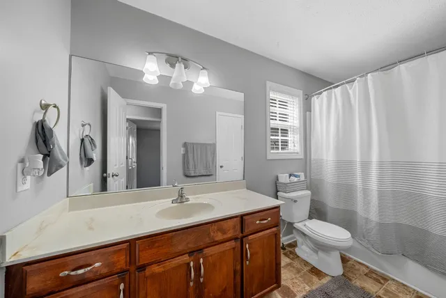 a bathroom with a granite countertop sink toilet a large mirror a shower and a bathtub