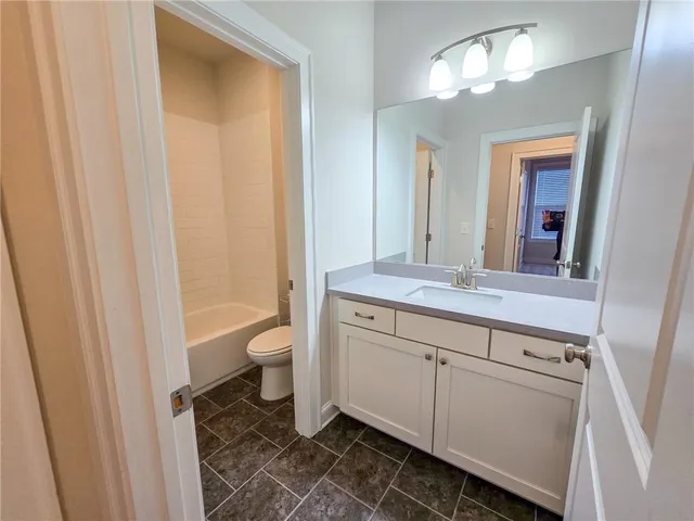 a bathroom with a granite countertop sink a toilet and a mirror
