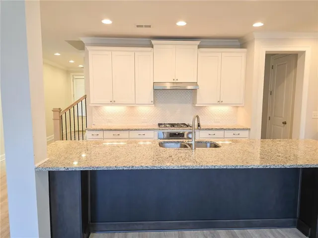 a large kitchen with stainless steel appliances granite countertop a sink dishwasher a stove and a refrigerator with wooden floor