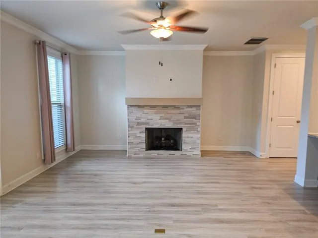 a view of an empty room with wooden floor and a fireplace
