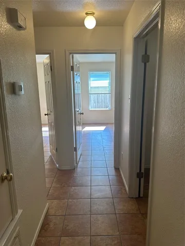 a view of a hallway with wooden floor and a bathroom