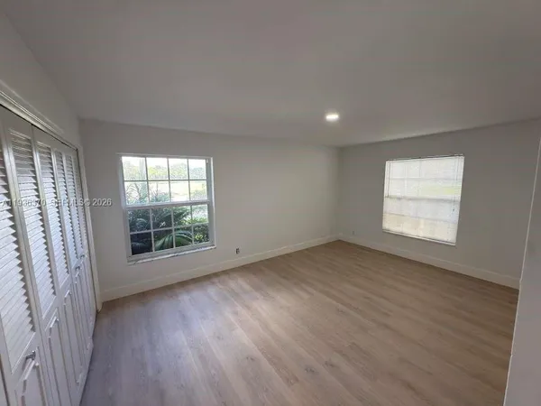 an empty room with wooden floor and windows