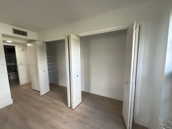 an empty room with closet and wooden door