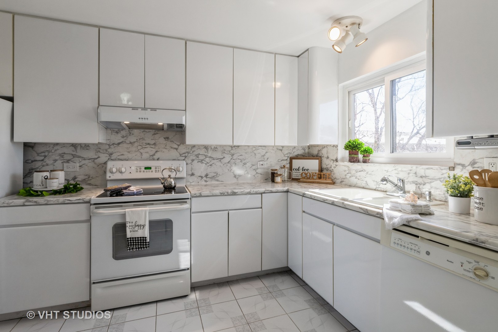 2205 West Nichols Road, Unit F Arlington Heights, IL 60004 - Photo 6 of 15 a kitchen with white cabinets stainless steel appliances a sink and a window