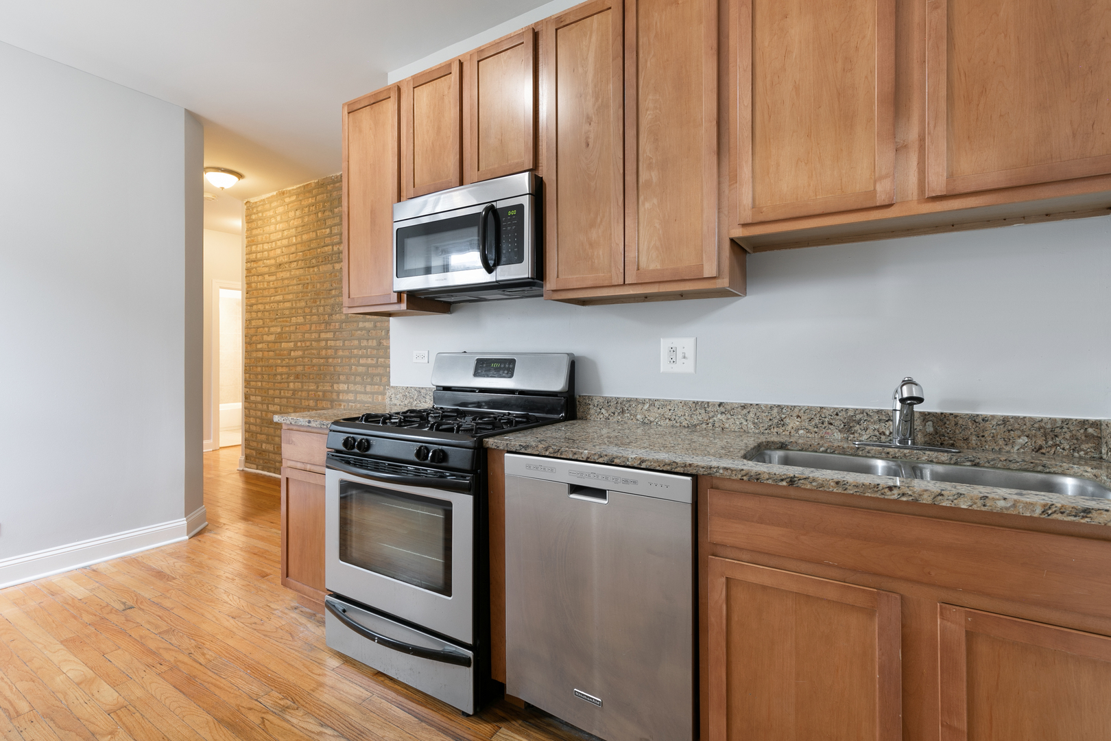 2011 West Jarvis Avenue, Unit 3 Chicago, IL 60645 - Photo 4 of 15 a kitchen with granite countertop stainless steel appliances a stove a microwave and cabinets