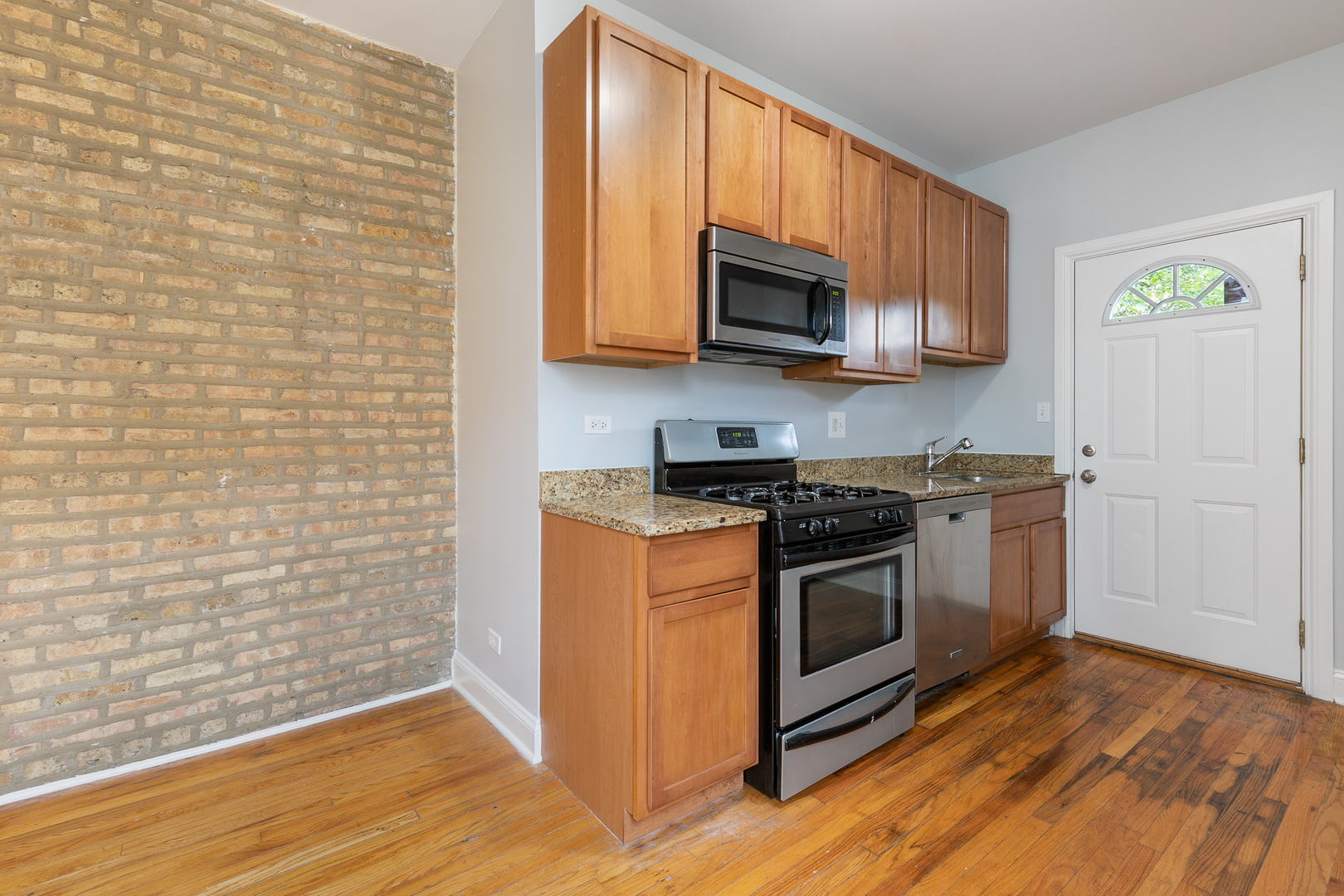 2011 West Jarvis Avenue, Unit 3 Chicago, IL 60645 - Photo 5 of 15 a kitchen with stainless steel appliances granite countertop a stove and a microwave