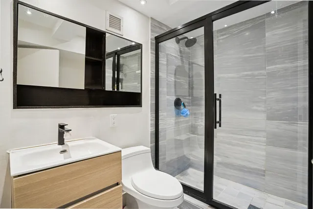 a bathroom with a sink a mirror a toilet and shower