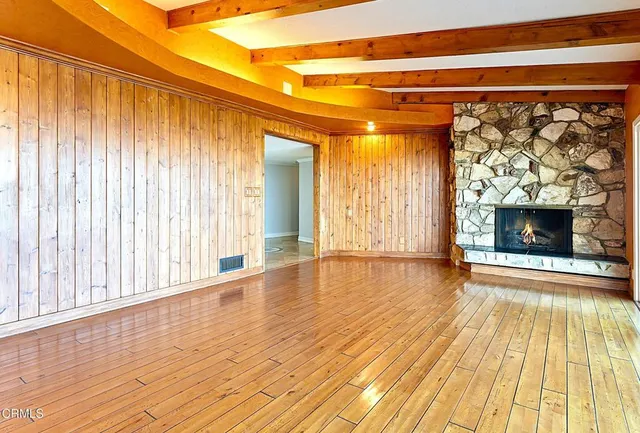 a view of empty room with wooden floor and fireplace