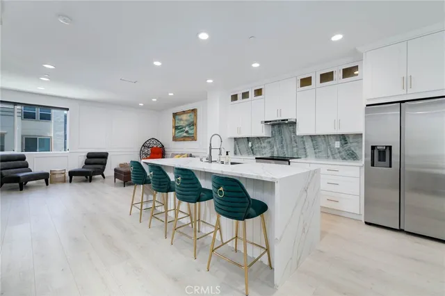 a kitchen with stainless steel appliances kitchen island granite countertop a refrigerator and a stove top oven with white cabinets