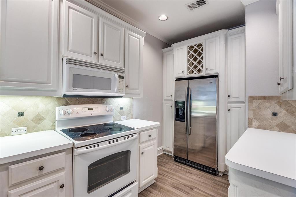 5325 Bent Tree Forest Drive, Unit 2244 Dallas, TX 75248 - Photo 2 of 15 a kitchen with white cabinets and stainless steel appliances