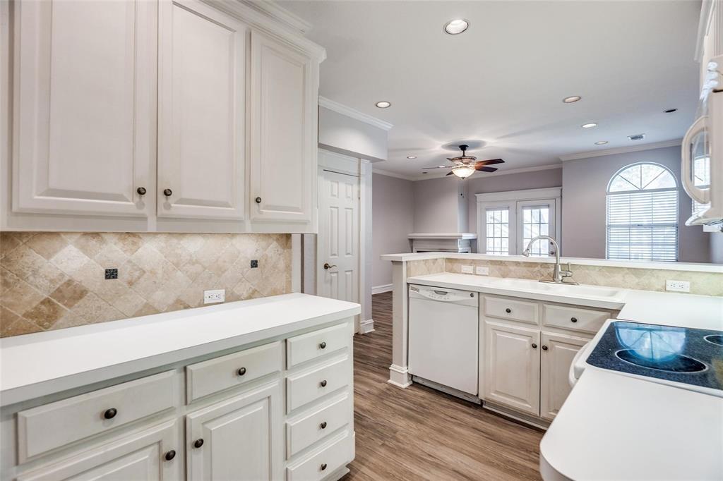 5325 Bent Tree Forest Drive, Unit 2244 Dallas, TX 75248 - Photo 3 of 15 a kitchen with a sink dishwasher and white cabinets with wooden floor