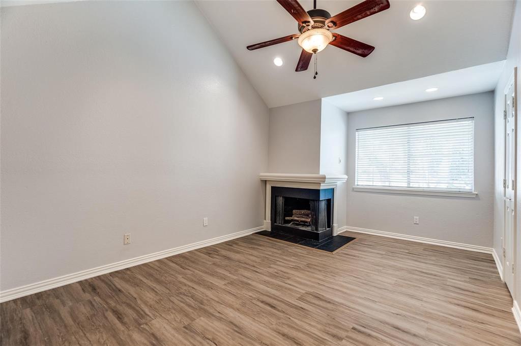 5325 Bent Tree Forest Drive, Unit 2244 Dallas, TX 75248 - Photo 6 of 15 wooden floor in an empty room with a fireplace and a ceiling fan