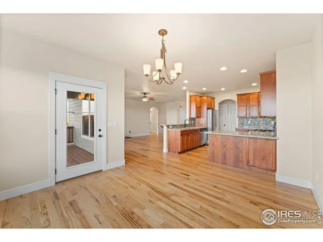 a view of a kitchen with granite countertop a refrigerator and a wooden floor