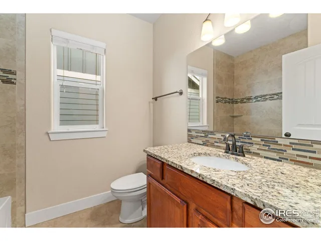 a bathroom with a granite countertop sink toilet and mirror