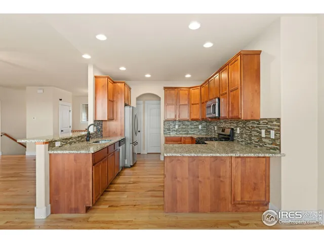 a large kitchen with stainless steel appliances kitchen island granite countertop a large kitchen island a stove a sink and a refrigerator