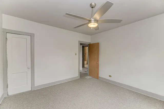 an empty room with a chandelier fan and closet area
