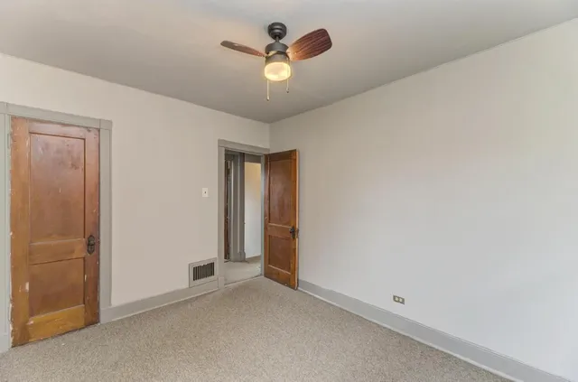 an empty room with closet and a ceiling fan