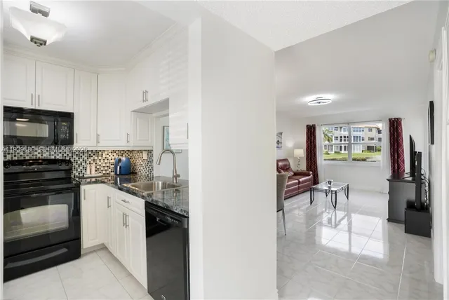 a kitchen with granite countertop white cabinets and black appliances