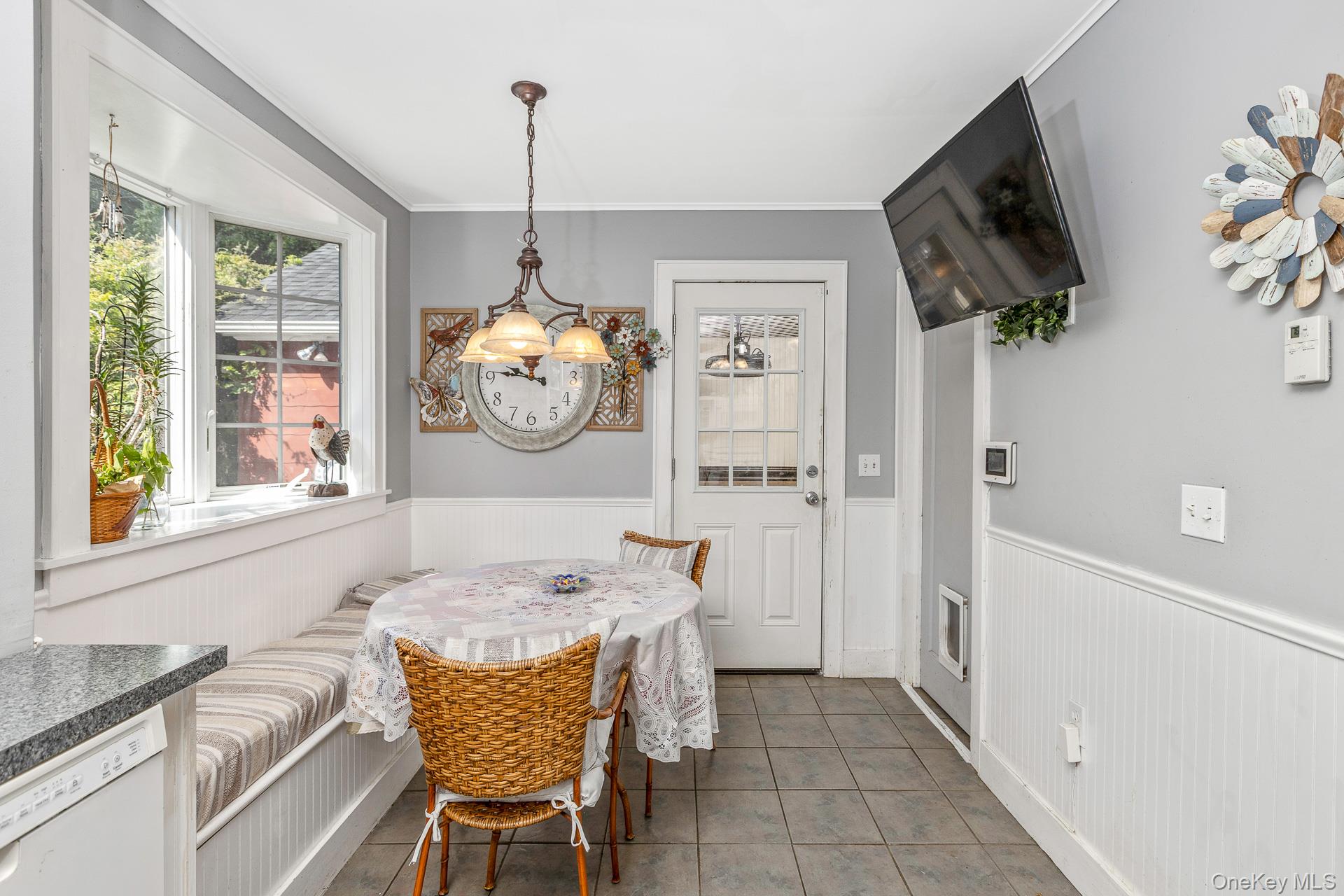 5660 Sound Avenue Mattituck, NY 11952 - Photo 18 of 43 Dining room with a wainscoted wall, a chandelier, tile patterned floors, crown molding, and breakfast area