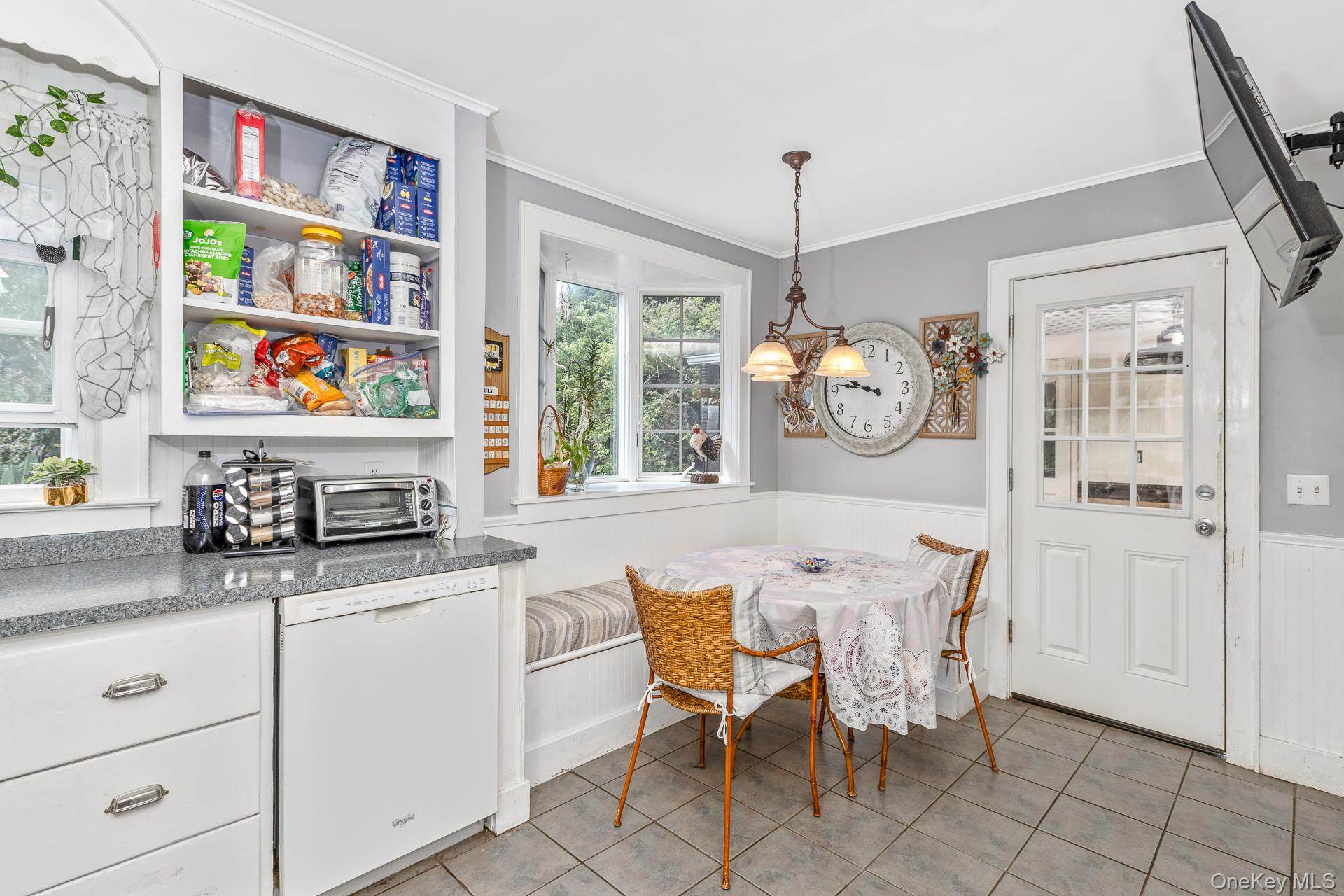 5660 Sound Avenue Mattituck, NY 11952 - Photo 19 of 43 Dining room featuring a wainscoted wall, a chandelier, crown molding, and light tile patterned floors