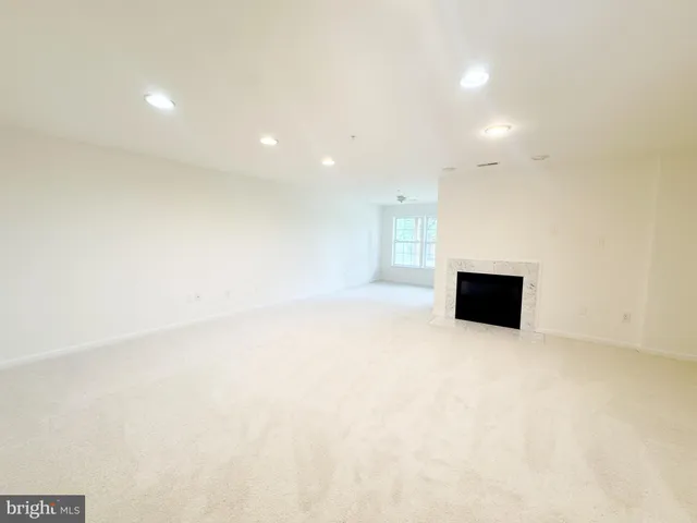 an empty room with windows and fireplace