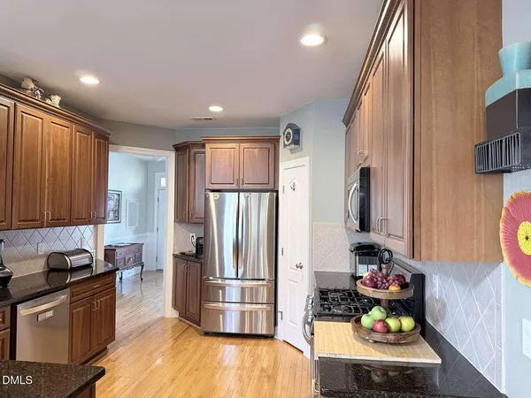 a kitchen with stainless steel appliances granite countertop a stove top oven a refrigerator and a view of living room