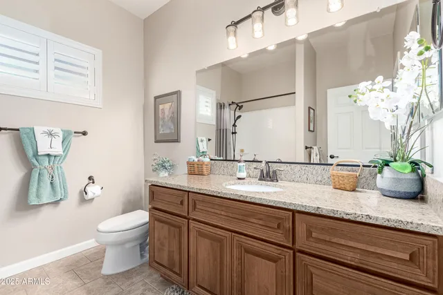 a bathroom with a granite countertop sink a toilet and a mirror