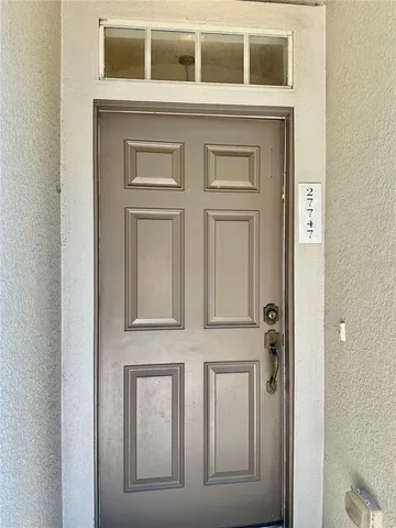 a view of an empty room with wooden floor and a ceiling fan