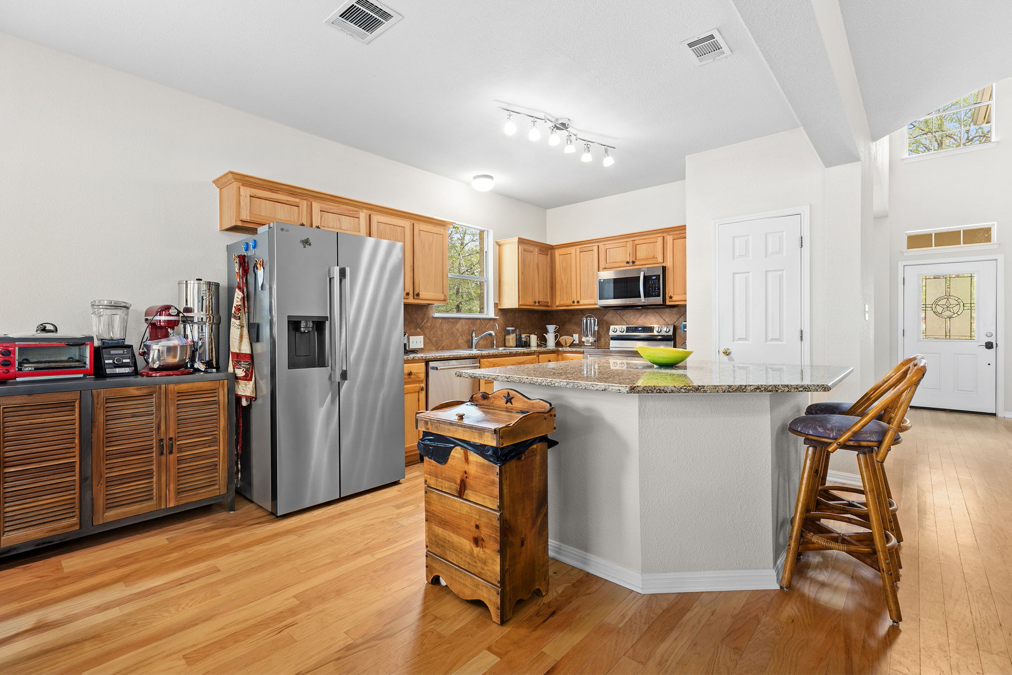 202 The Oaks Boulevard Elgin, TX 78621 - Photo 17 of 40 Kitchen featuring stainless steel appliances, light stone countertops, light wood-style flooring, a center island, and a breakfast bar area
