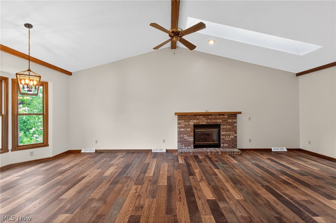 5346 Burlawn Street Northwest Canton, OH 44708 - Photo 6 of 40 Vaulted ceiling living area featuring wood-finish flooring, a brick fireplace with hearth, and a rectangular skylight