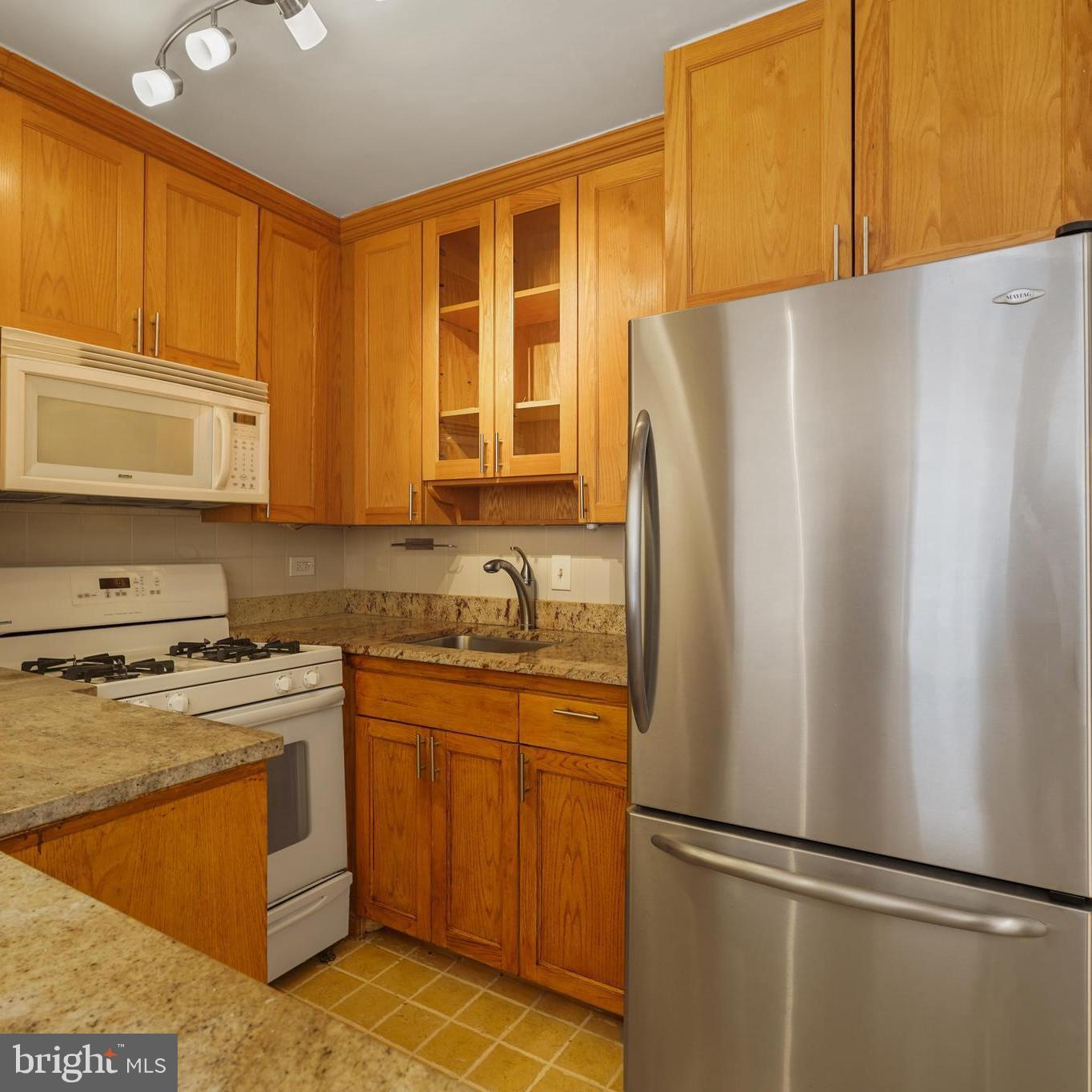 1260 21st Street Northwest, Unit 306 Washington, DC 20036 - Photo 7 of 23 a kitchen with stainless steel appliances granite countertop a refrigerator sink and cabinets