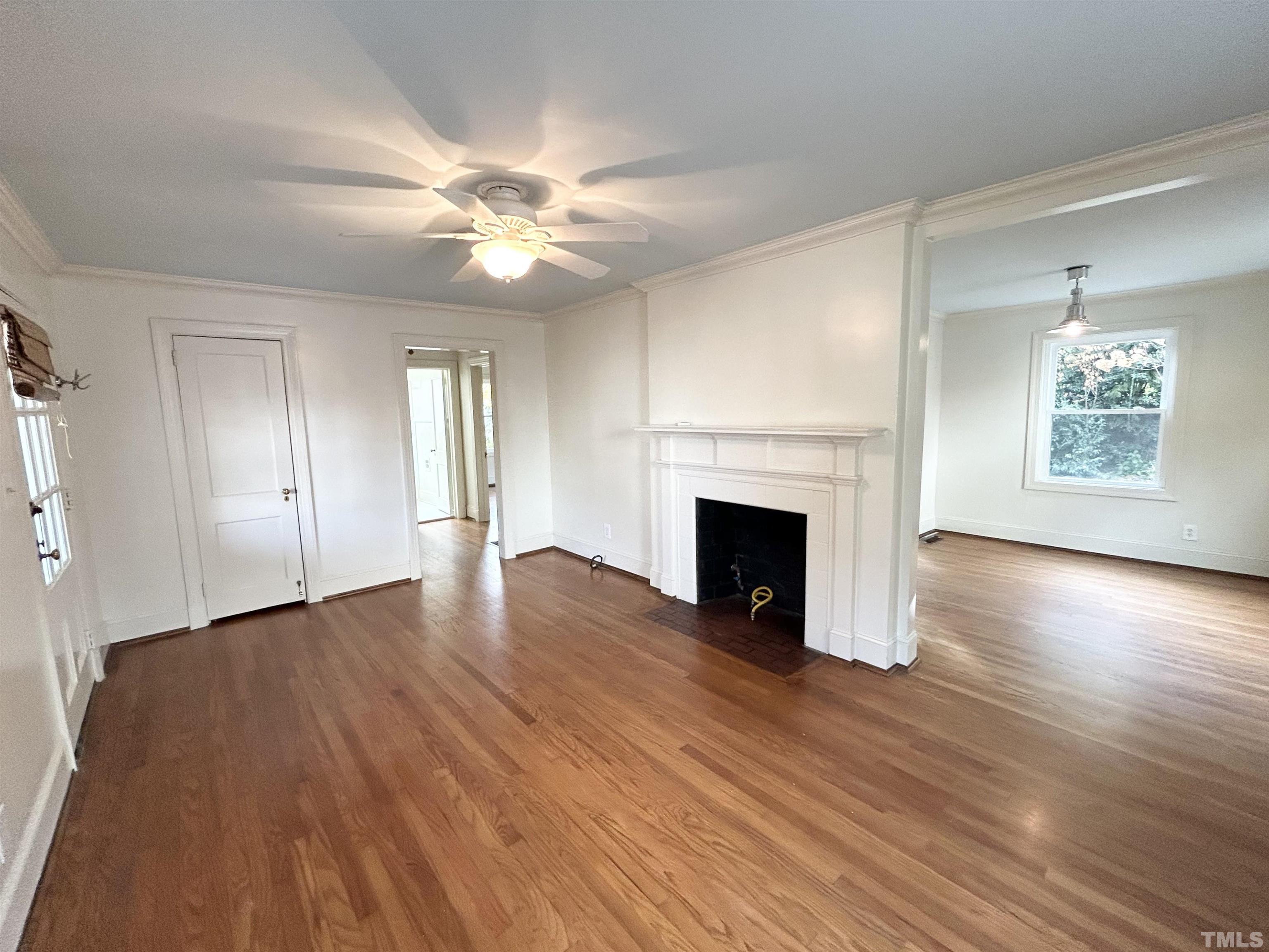 1607 Carson Street Raleigh, NC 27608 - Photo 2 of 17 an empty room with wooden floor fireplace and windows