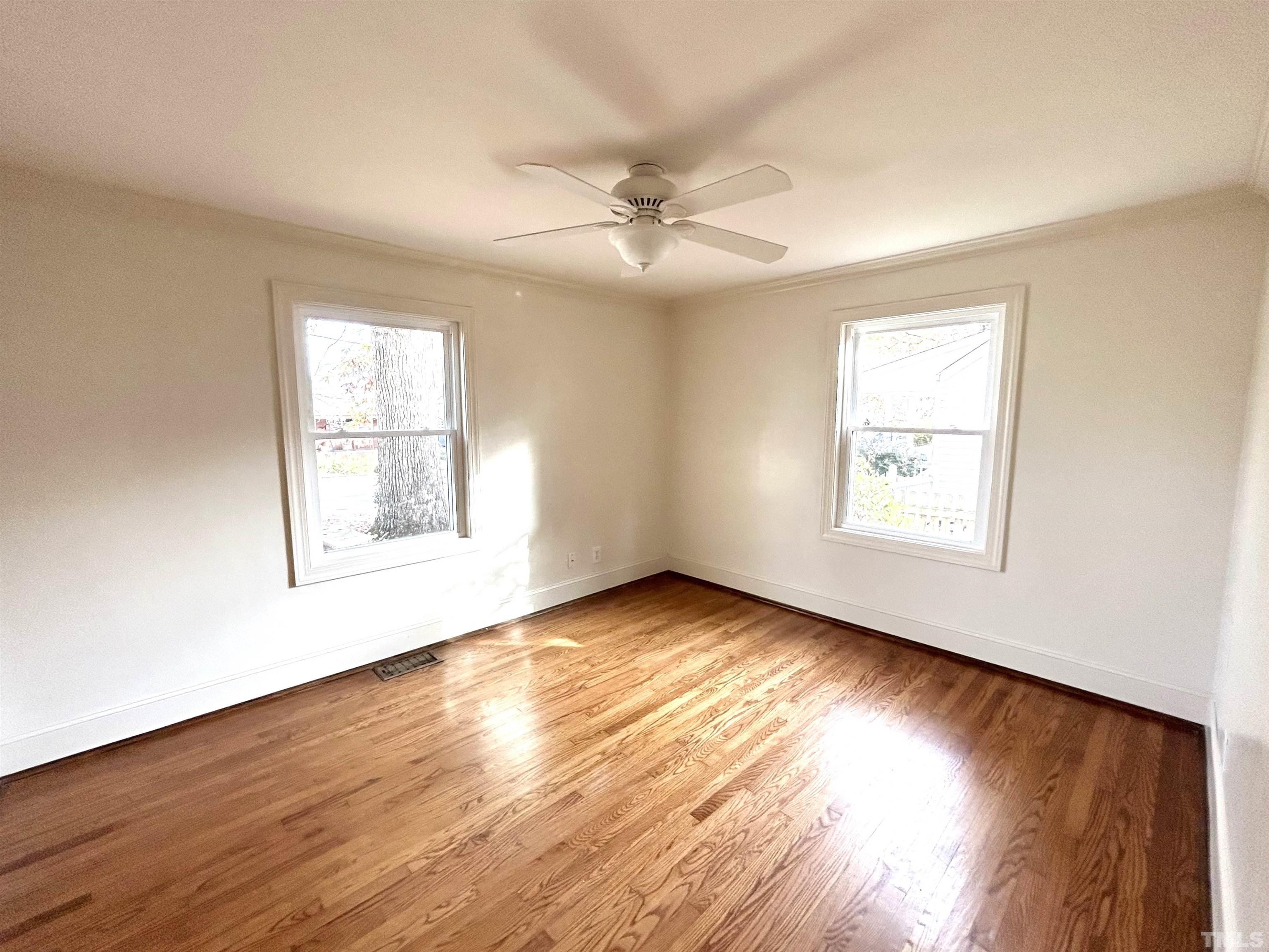 1607 Carson Street Raleigh, NC 27608 - Photo 8 of 17 an empty room with wooden floor chandelier fan and windows