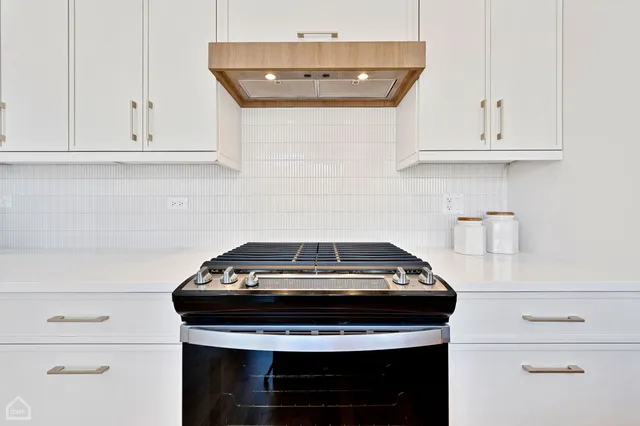 a kitchen with a stove and white cabinets