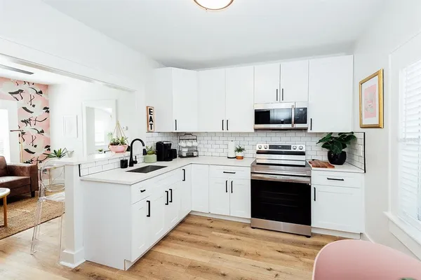 a kitchen with stainless steel appliances white cabinets and wooden floor