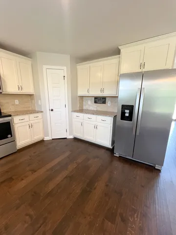 a kitchen with stainless steel appliances granite countertop a stove top oven a sink and white cabinets