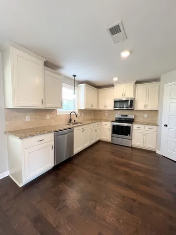 a kitchen with granite countertop a sink cabinets stainless steel appliances and a window