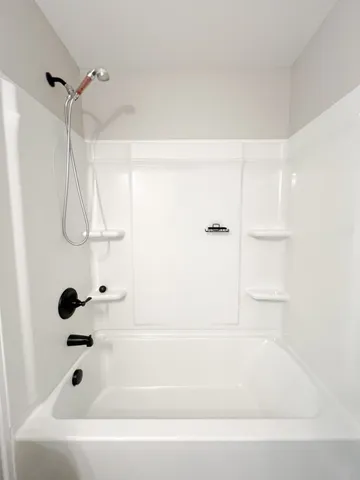 an empty room with chandelier fan and windows