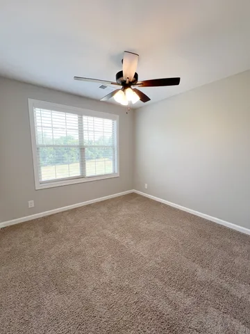 en empty room with windows and chandelier fan