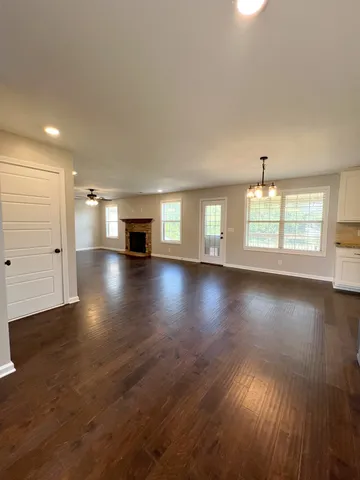 an empty room with windows fireplace and wooden floor